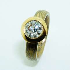 18k white and yellow gold mokume gane court band with brilliant cut diamond in 22k gold pod rubover setting