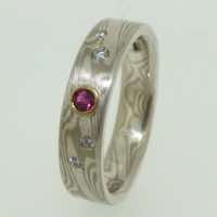 18k white gold and silver mokume gane flat band with flush set diamonds and a round ruby in a low 22k gold rub-over setting.