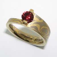18k white and yellow gold mokume gane asymmetric tapered band with a ruby in a 22k gold bar setting