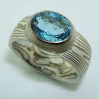 18k white gold and silver mokume gane full court band with an oval harlequin cut aquamarine in a low rub-over setting.