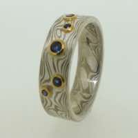 18k white gold and silver mokume gane flat band with blue sapphires in low 22k gold rub-over settings.