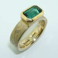 18k white and yellow gold mokume gane flat band with an emerald cut green tourmaline in an 18k yellow gold setting