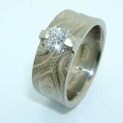 Platinum textured wide band with brilliant cut diamond in bar setting.  POA.