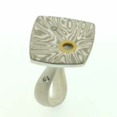 18k white gold and silver mokume gane fower neukit with cutaway detail and diamonds presented on a sterling silver curved band.