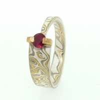 22k gold, 18k white gold and silver mokume gane tapered band with a ruby in a 22k gold bar setting