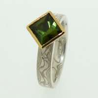 18k white gold and silver mokume gane flat band with flush set diamonds and a square green tourmaline in a 22k gold rub-over box setting.