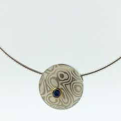 18k white gold and silver mokume gane small discus pendant with blue sapphire set in 22k gold.