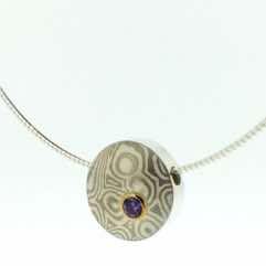 18k white gold and silver mokume gane small discus pendant with lilac sapphire set in 22k gold. 