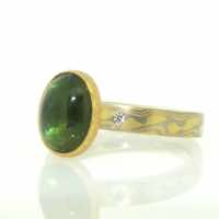 18k white and yellow gold mokume gane flat band with oval green tourmaline cabochon in 22k gold rubover setting with small flush-set diamonds on shoulders