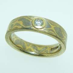 18k white and yellow gold mokume gane band with brilliant cut diamond in very low 18k yellow gold rubover setting