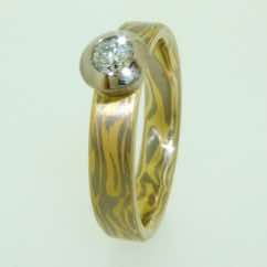18k white and yellow gold mokume gane flat band with brilliant cut diamond in 18k white gold tapered rubover setting