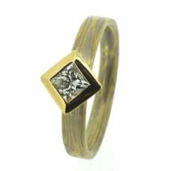 18k white and yellow gold mokume gane 3mm flat band with a princess cut diamond in an 18k yellow gold box setting