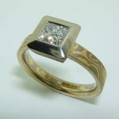 18k white and yellow gold mokume gane 3mm flat band with a princess cut diamond in an 18k white gold box setting