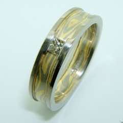 18k white and yellow gold mokume gane flat band with 18k white gold rails set with a princess cut diamond