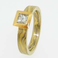 18k white and yellow gold mokume gane flat band with a princess cut diamond in a 22k gold box setting