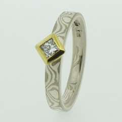 18k white gold and silver mokume gane 3mm flat band with a princess cut diamond in an 18k yellow gold box setting